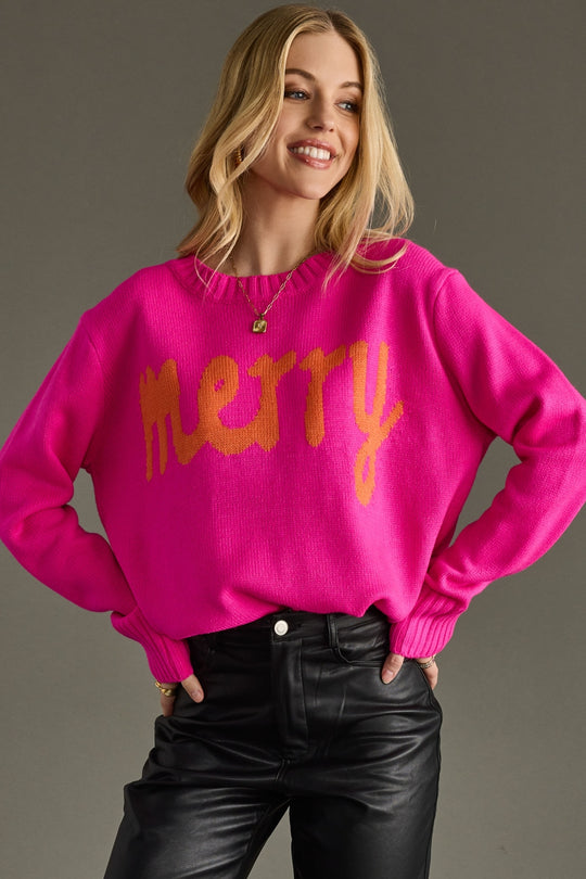 Woman wearing a bright pink sweater with 'Merry' text on a gray background