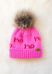 Pink knit hat with red text and fur pom-pom on a white background
