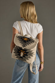 Person wearing a backpack with a geometric pattern on a plain background