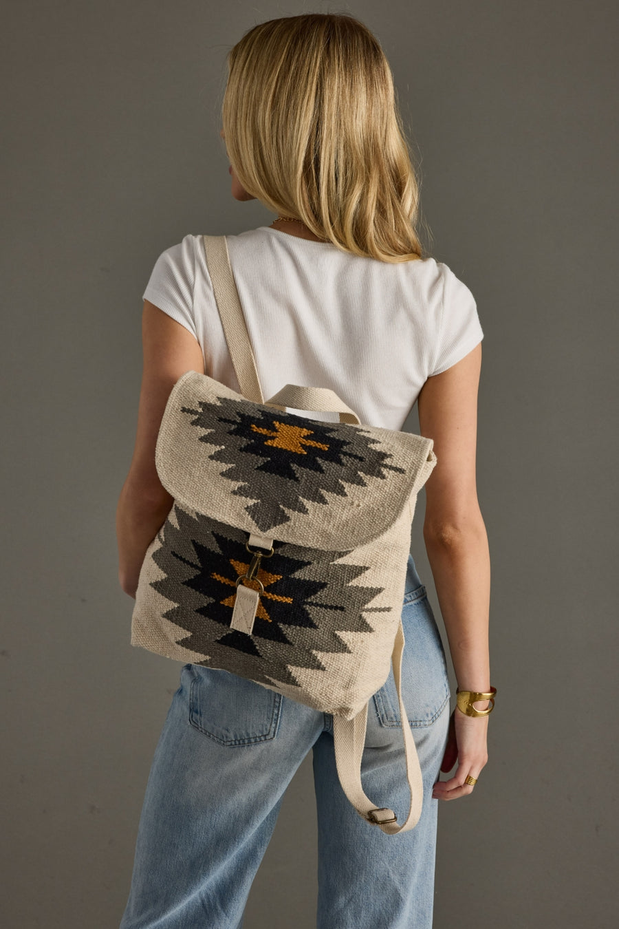 Person wearing a backpack with a geometric pattern on a plain background