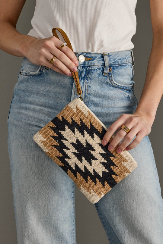 Person holding a patterned pouch with jeans and a white top