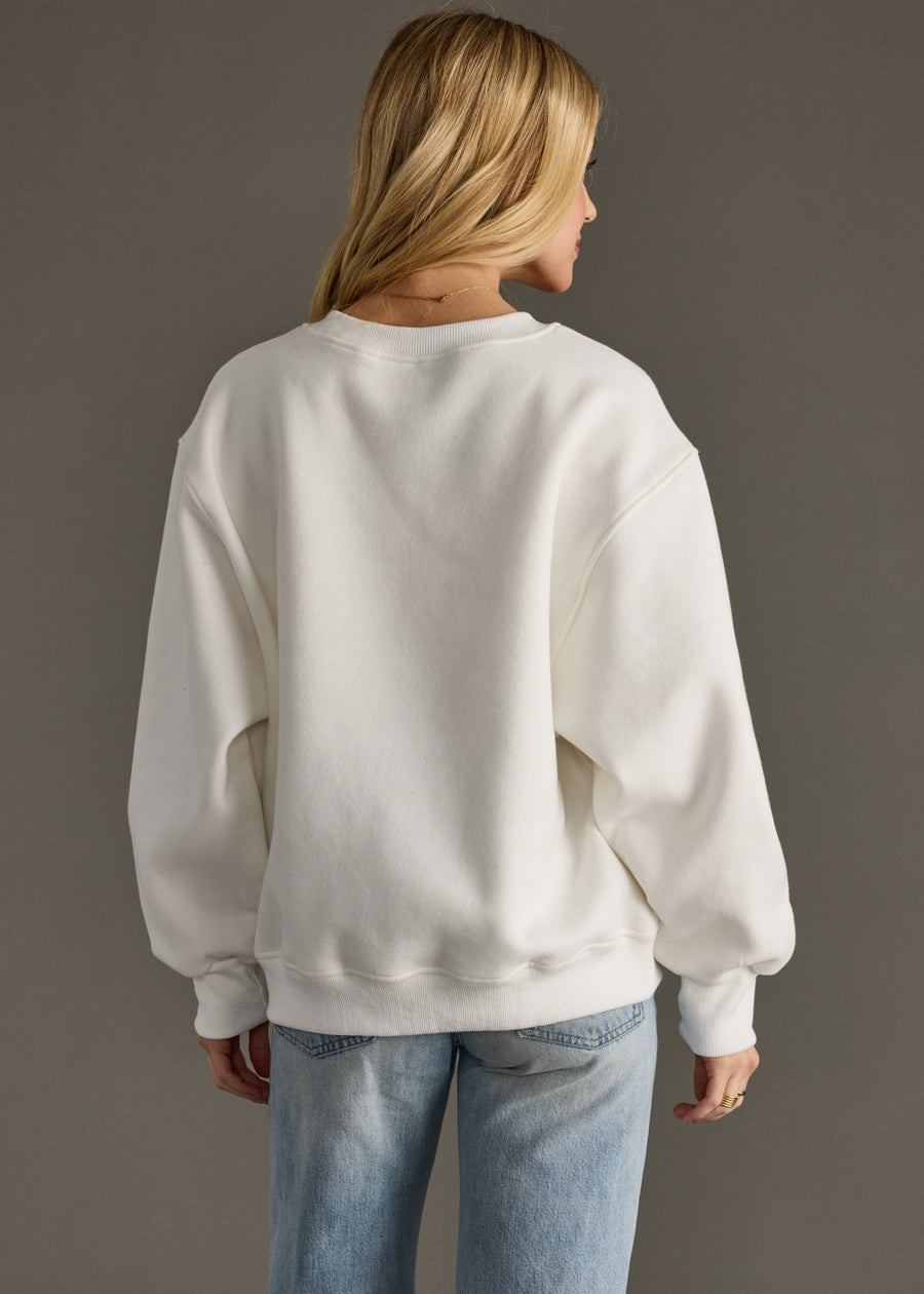 Person wearing a white sweatshirt and light blue jeans against a gray background