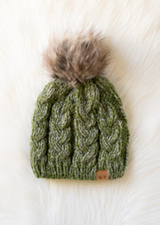 Green knitted beanie with a fur pom-pom on a white background