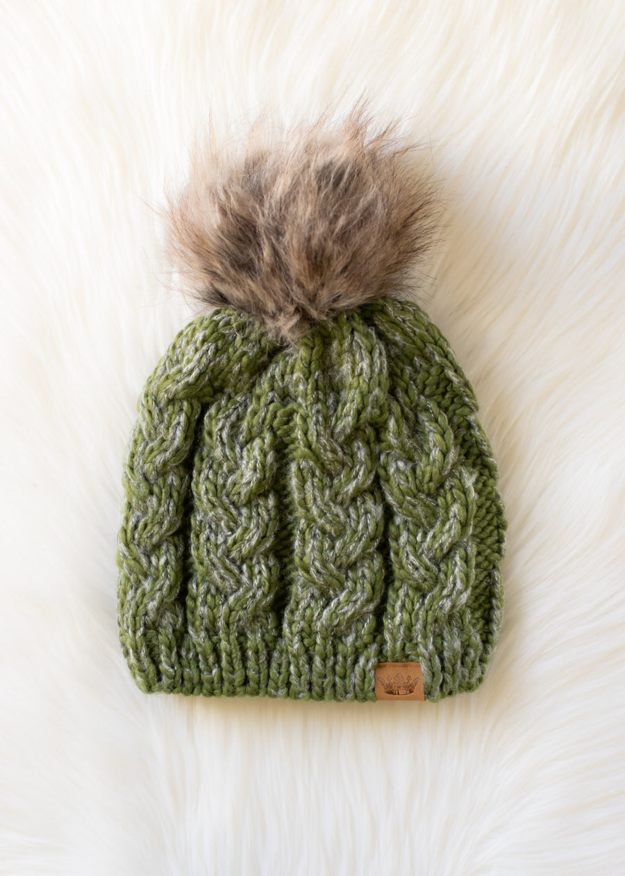 Green knitted beanie with a fur pom-pom on a white background
