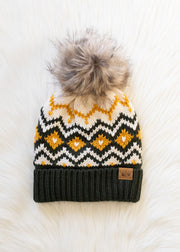 Knit beanie with a patterned top and fur pom-pom on a white background
