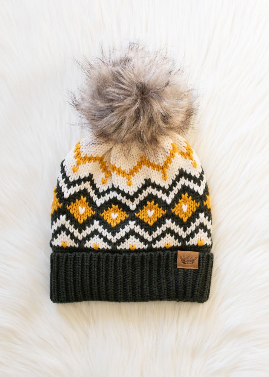 Knit beanie with a patterned top and fur pom-pom on a white background