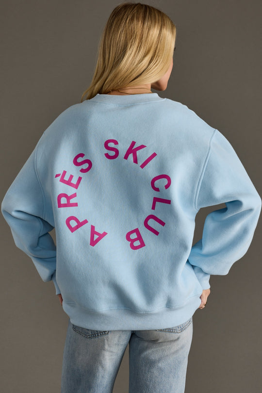 Person wearing a light blue sweatshirt with pink text on the back against a gray background
