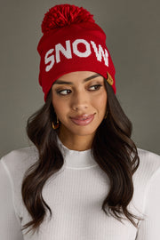 Woman wearing a red beanie with 'SNOW' text on a gray background