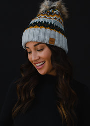 Woman wearing a patterned beanie with a pom-pom against a black background