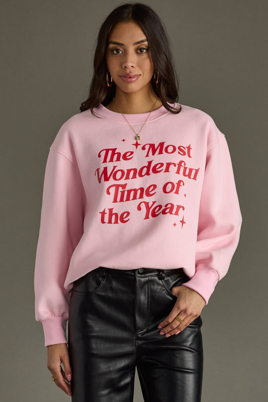 Person wearing a pink sweatshirt with red text on a gray background