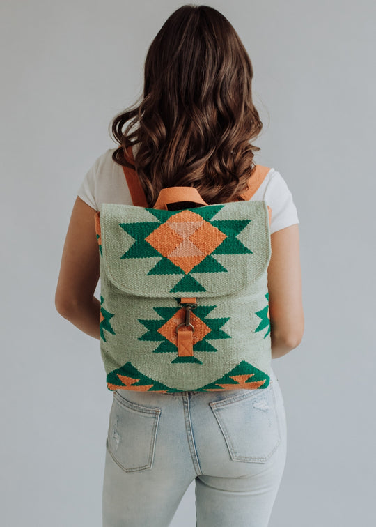 Person wearing a green and orange patterned backpack against a plain background