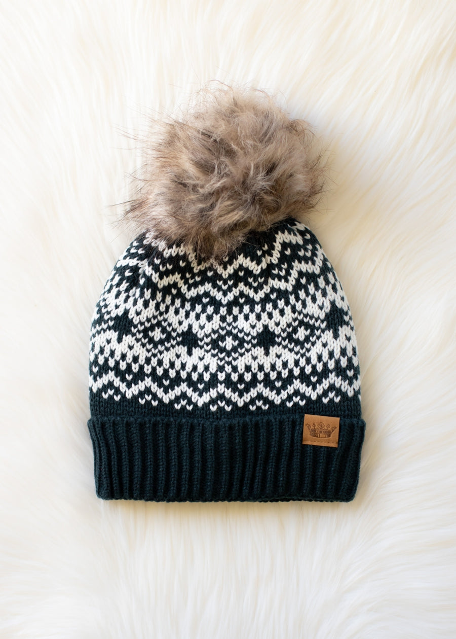 Knitted beanie with a pattern and fur pom-pom on a white background