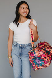 Woman holding a colorful floral bag against a gray background