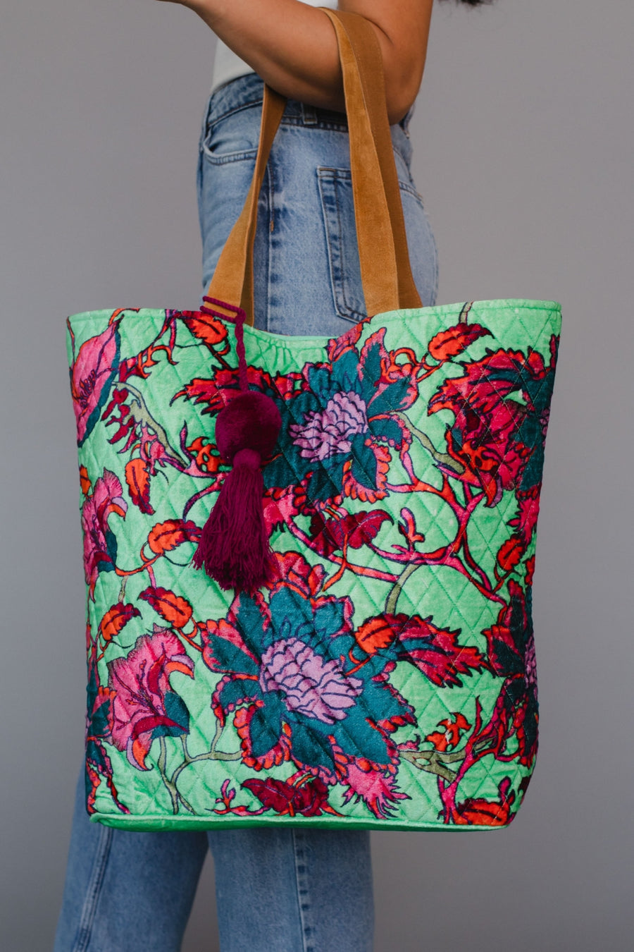 Floral patterned tote bag held by a person against a gray background