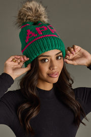 Woman wearing a green beanie with a pom-pom, posing against a neutral background
