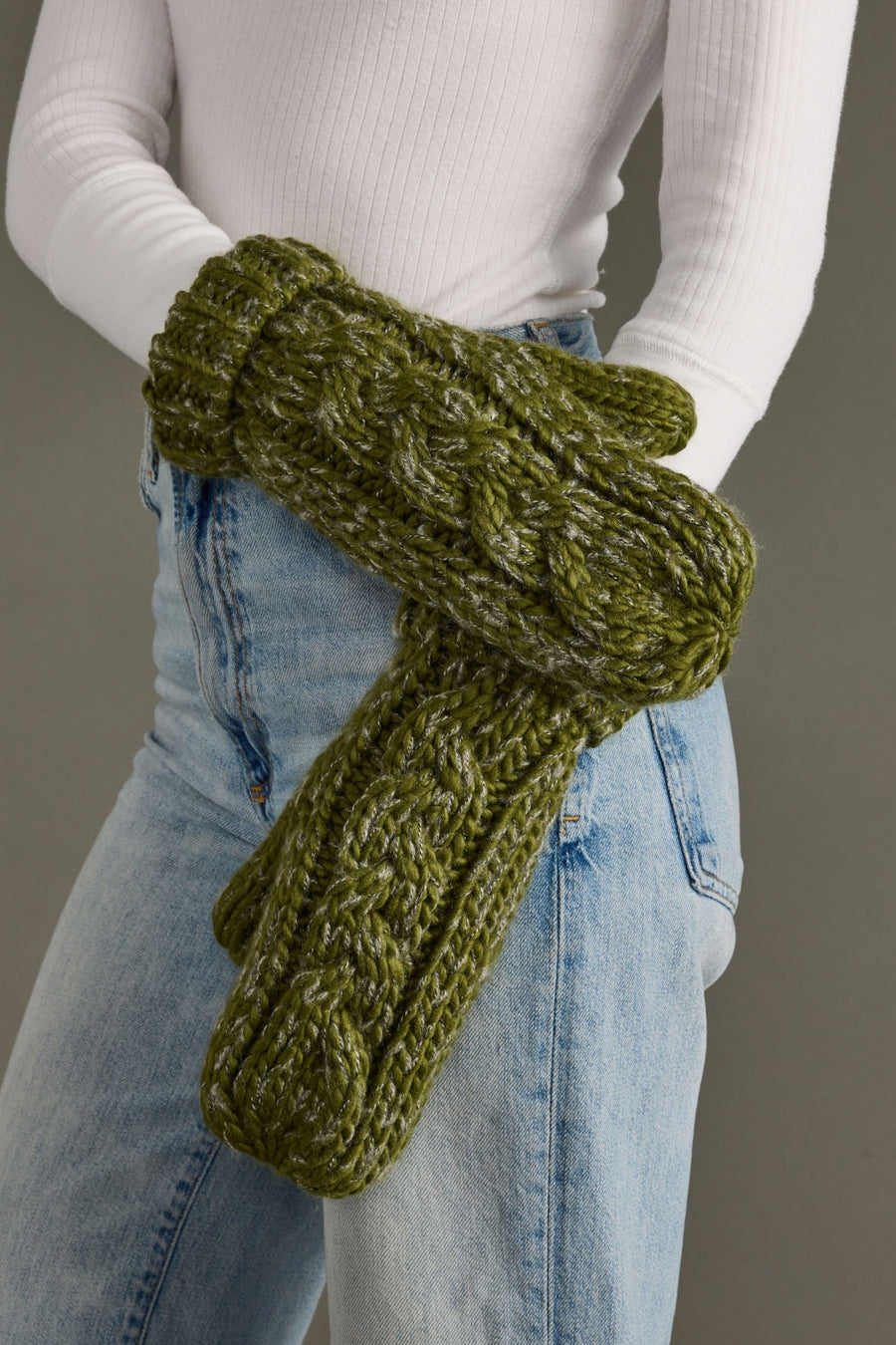 Green knit mittens worn by a person with a neutral background