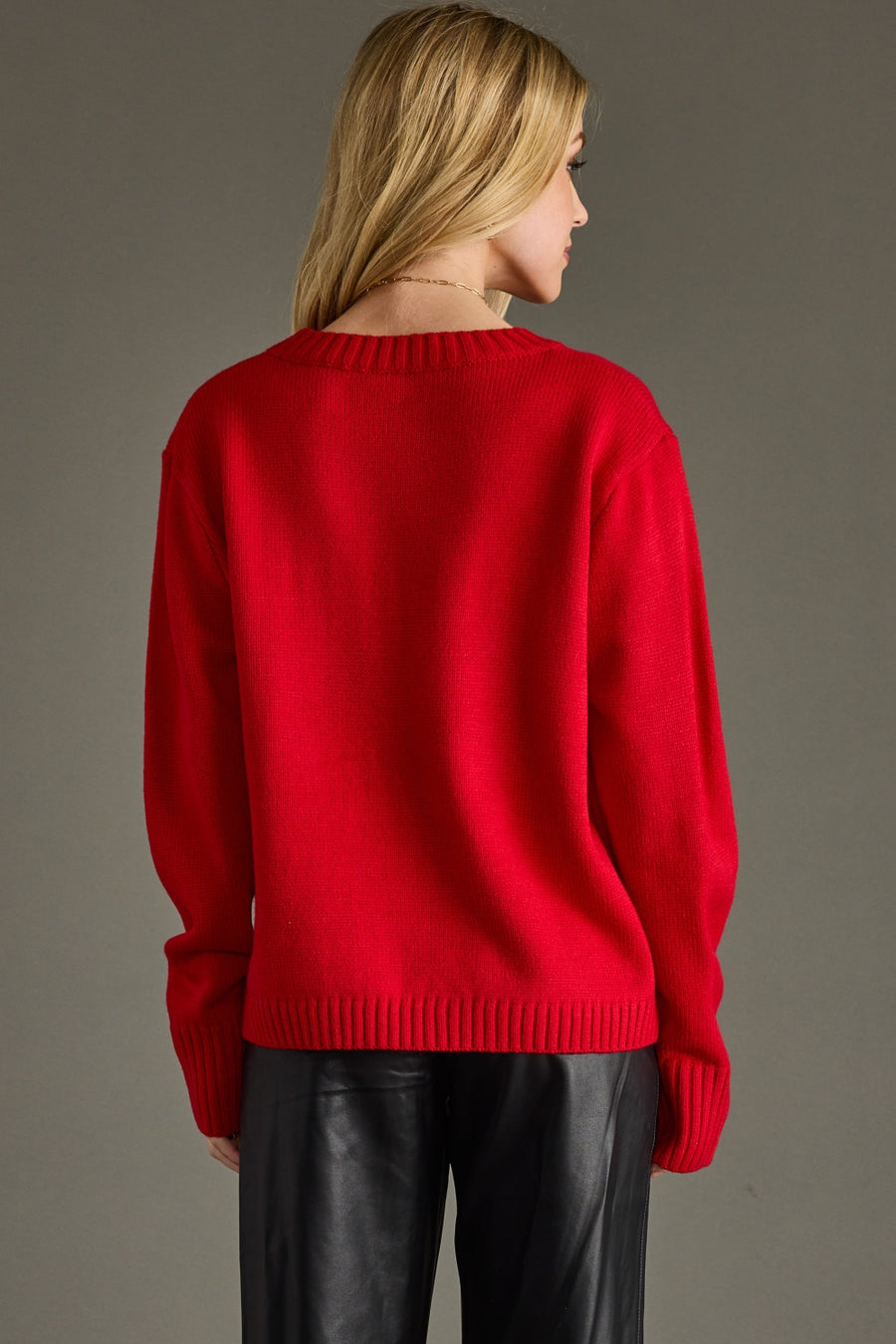 Person wearing a red sweater and black pants against a gray background
