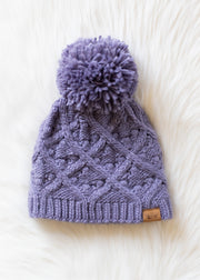 Purple knitted beanie with a pom-pom on a white background