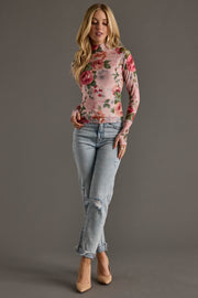 Woman wearing a floral top and jeans on a gray background