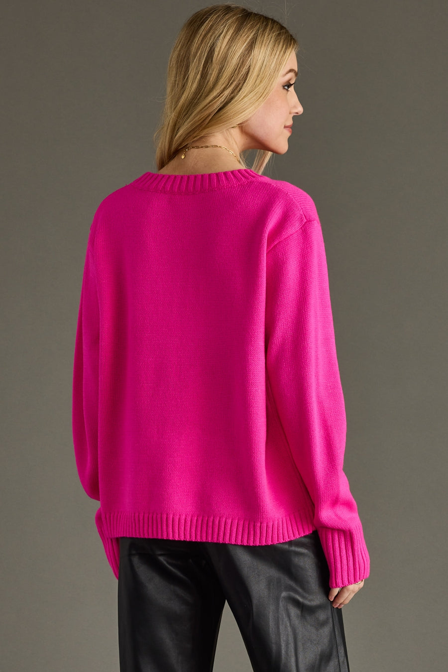 Woman wearing a bright pink sweater against a gray background