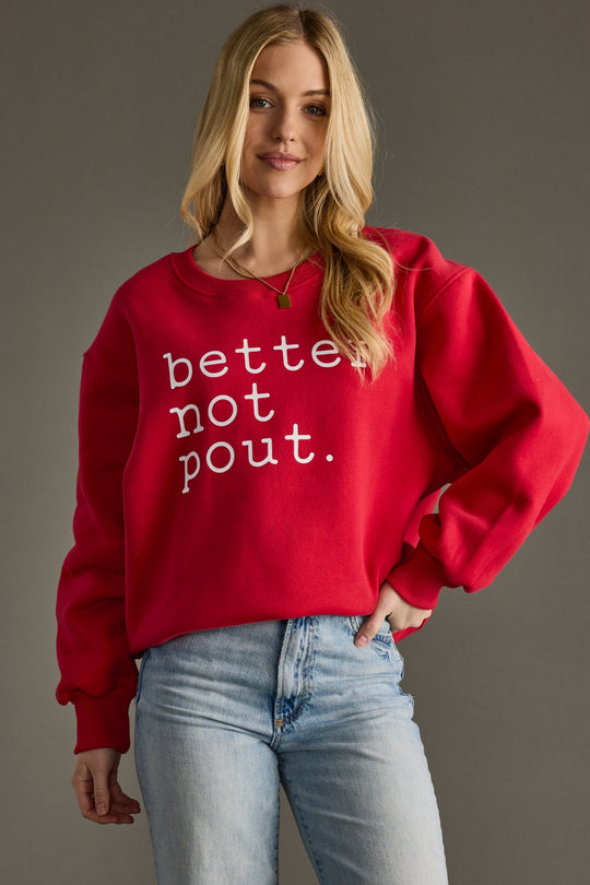 Woman wearing a red sweatshirt with 'better not pout' text on a gray background
